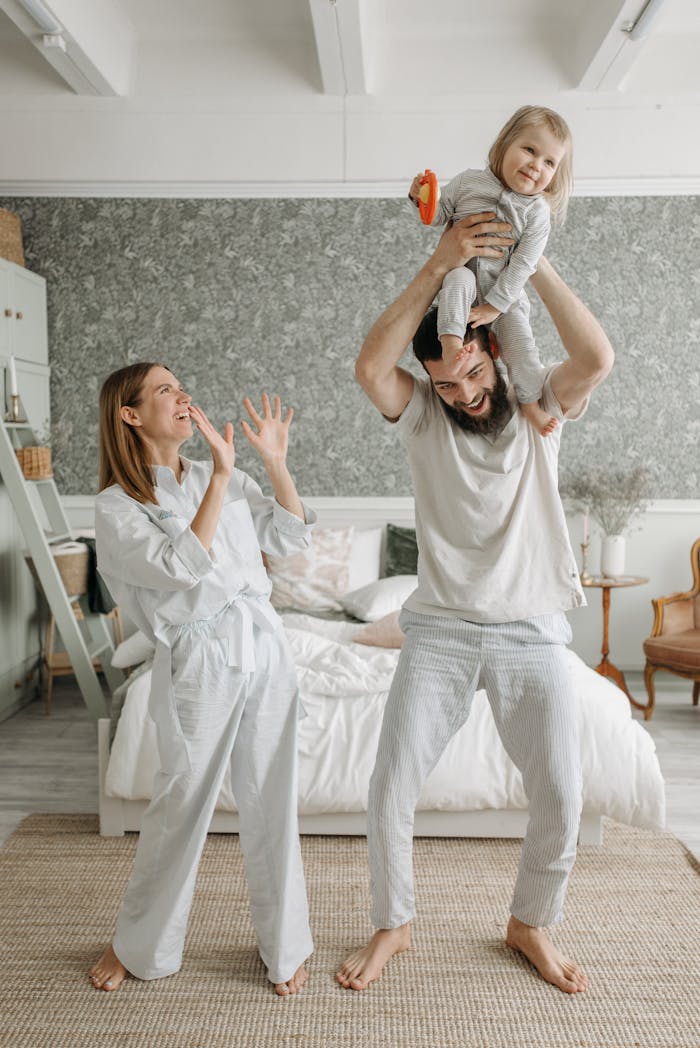 A joyful family in loungewear plays in their cozy bedroom, filled with laughter and bonding.